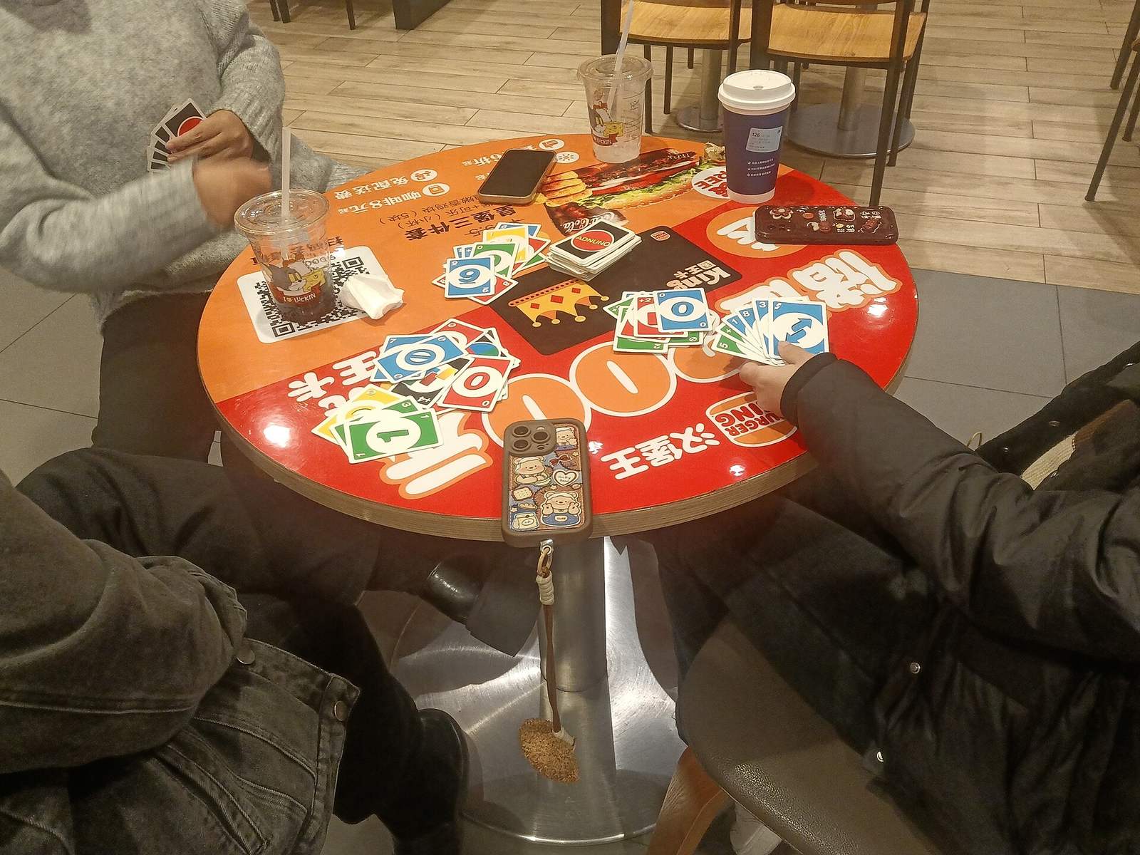 People playing a card game around a round red table